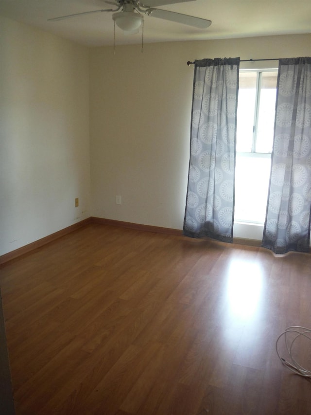 empty room with wood finished floors, ceiling fan, and baseboards