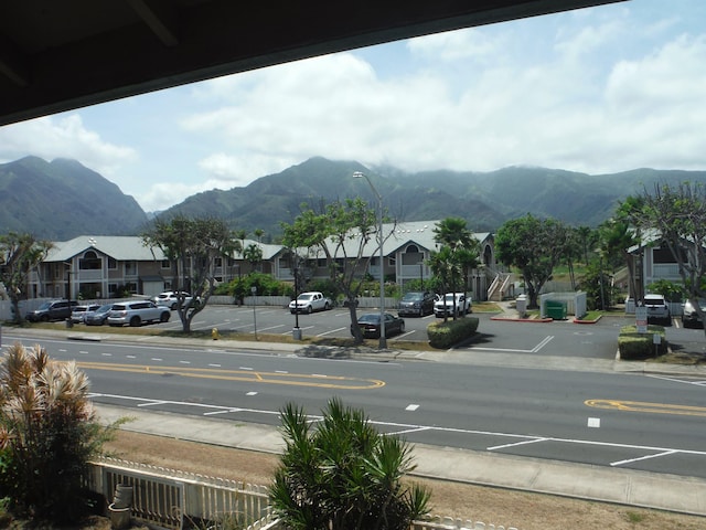 view of road with sidewalks, a mountain view, and street lighting