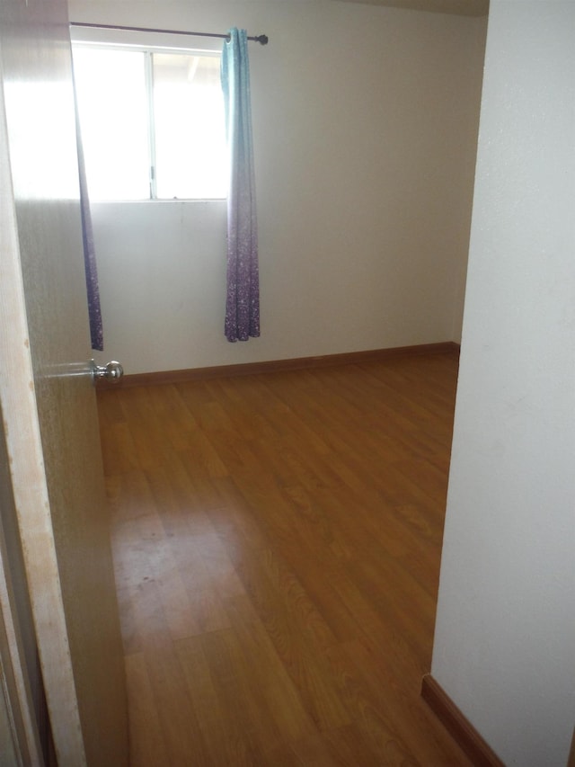 unfurnished room featuring baseboards and wood finished floors