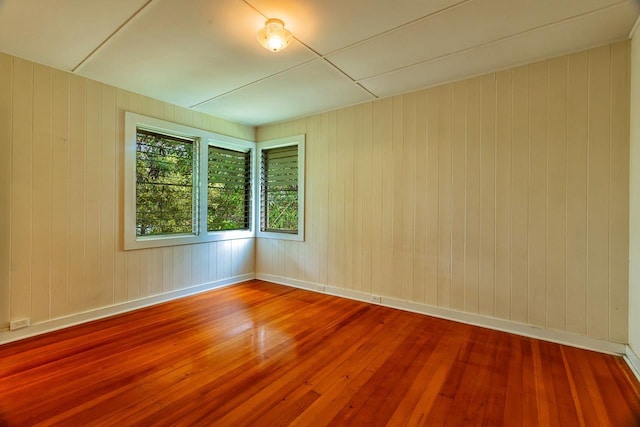 spare room with hardwood / wood-style floors and wooden walls