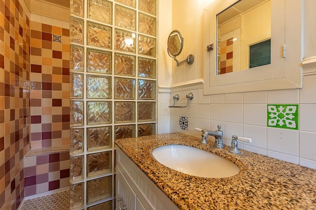 bathroom with tiled shower, vanity, and decorative backsplash