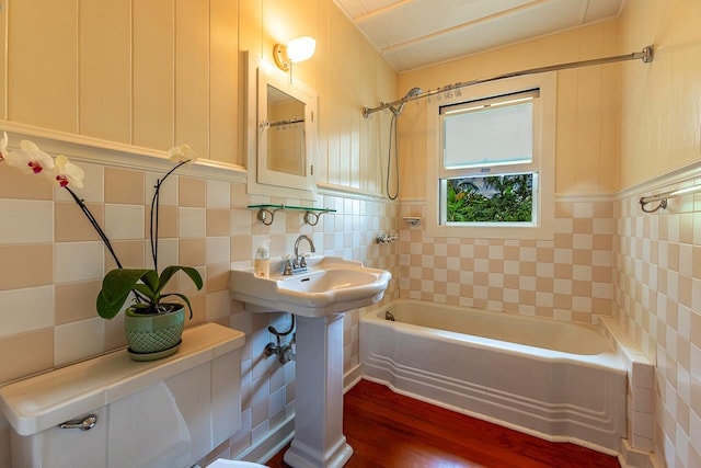 bathroom with tile walls, tiled shower / bath combo, wood-type flooring, and toilet