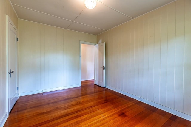 unfurnished room with hardwood / wood-style flooring and wood walls