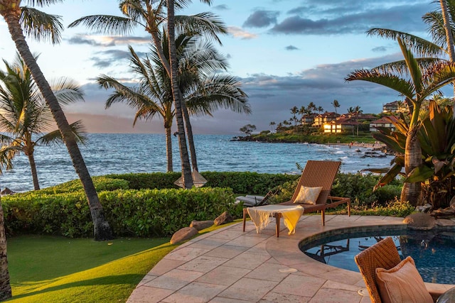 pool at dusk with a water view, a yard, and a patio area