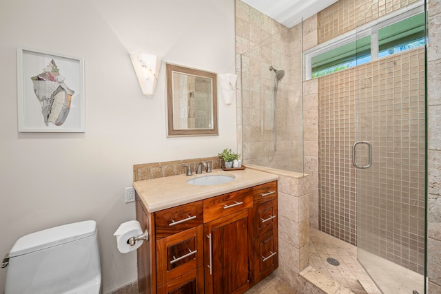 bathroom featuring vanity, a shower with shower door, and toilet