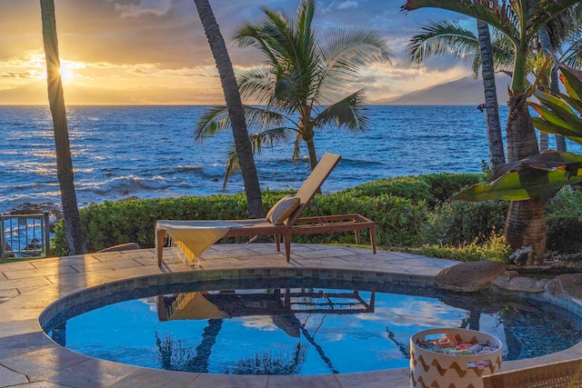 pool at dusk featuring a water view