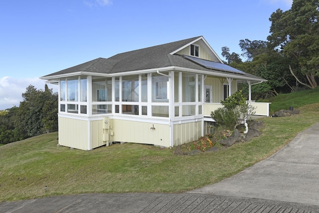 view of side of property featuring a sunroom and a lawn