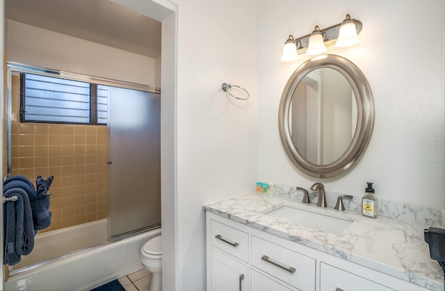 full bathroom with tile patterned floors, bath / shower combo with glass door, vanity, and toilet