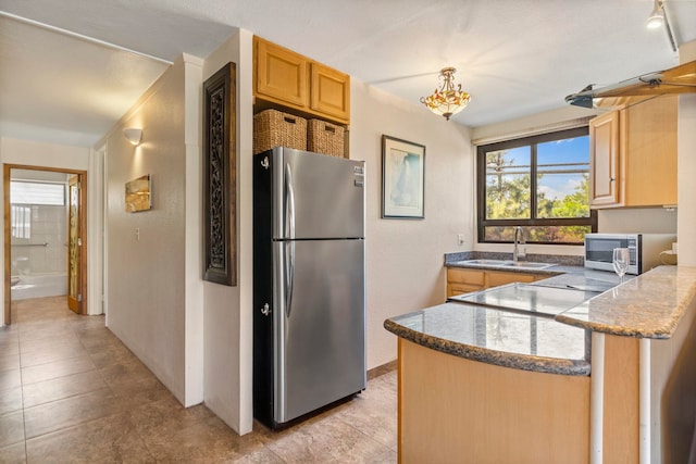 kitchen featuring appliances with stainless steel finishes, decorative light fixtures, sink, kitchen peninsula, and light brown cabinets