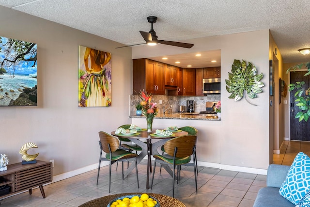 tiled dining area featuring sink, a textured ceiling, and ceiling fan