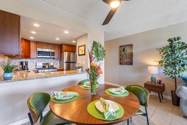 tiled dining room with ceiling fan, sink, and a textured ceiling