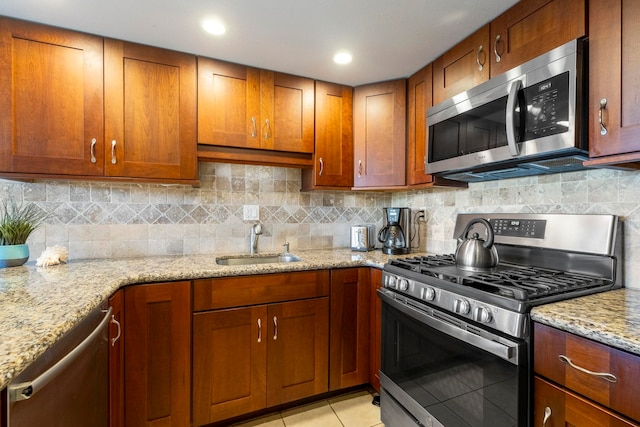 kitchen featuring sink, light tile patterned floors, stainless steel appliances, and light stone countertops