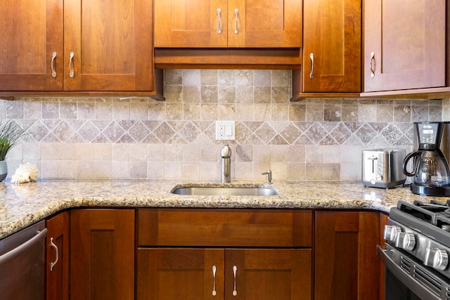 kitchen featuring tasteful backsplash, stainless steel appliances, light stone countertops, and sink