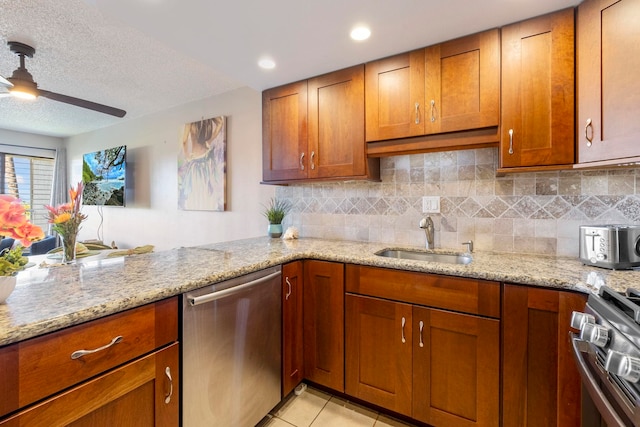 kitchen featuring dishwasher, sink, stove, light tile patterned floors, and light stone counters