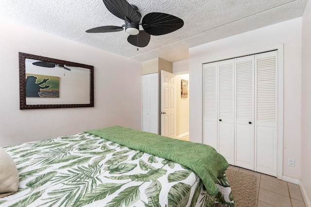 tiled bedroom with ceiling fan and a textured ceiling