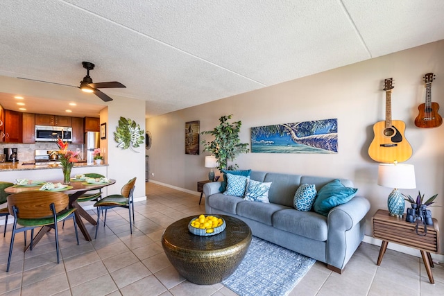 living room with ceiling fan, a textured ceiling, and light tile patterned floors