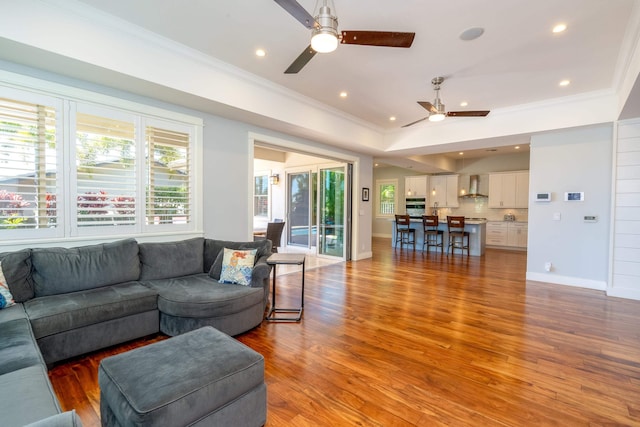 living room featuring light wood-style floors, a ceiling fan, and ornamental molding