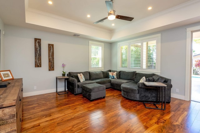 living room with a tray ceiling, baseboards, dark wood-style floors, and crown molding