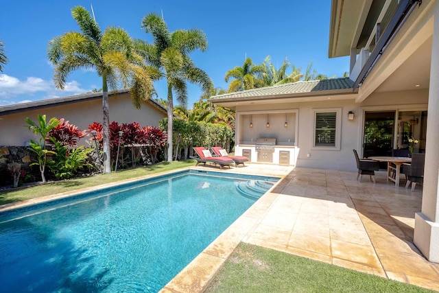 view of pool featuring a fenced in pool, a grill, an outdoor kitchen, and a patio area