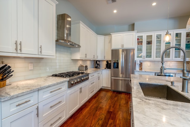 kitchen with dark wood-style floors, a sink, white cabinets, appliances with stainless steel finishes, and wall chimney range hood