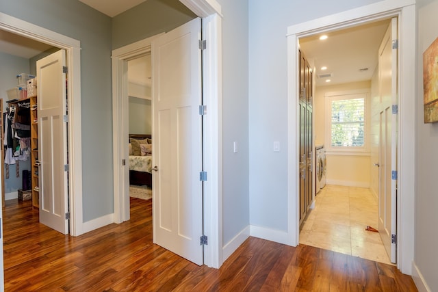 corridor with recessed lighting, washer / clothes dryer, wood finished floors, and baseboards