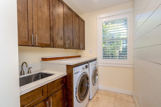 washroom featuring washer and dryer, cabinet space, baseboards, and a sink
