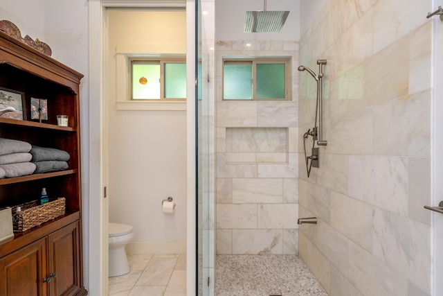 full bathroom featuring baseboards, toilet, and a tile shower