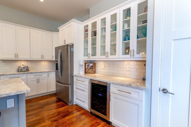 kitchen with dark wood-type flooring, beverage cooler, tasteful backsplash, white cabinetry, and stainless steel fridge