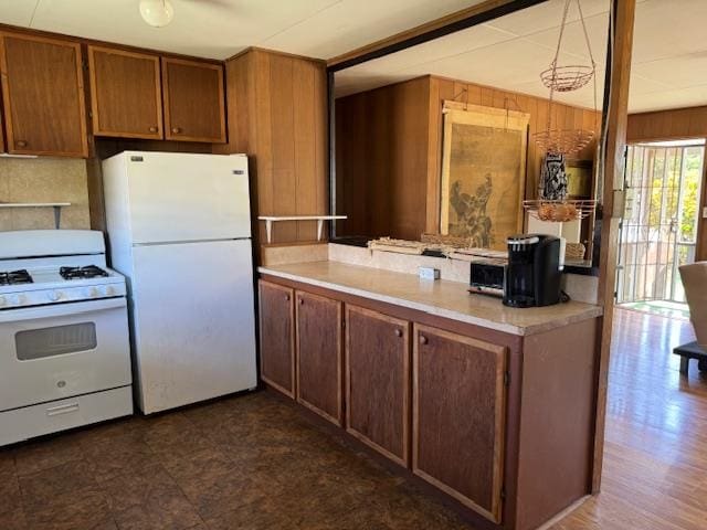 kitchen featuring pendant lighting, white appliances, and wooden walls