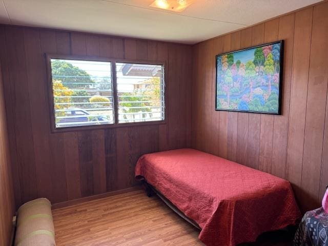 bedroom featuring light hardwood / wood-style floors and wood walls