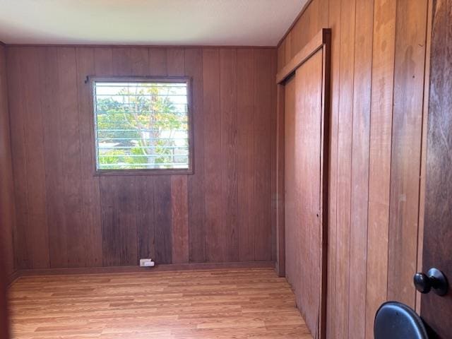 empty room featuring light wood-type flooring and wooden walls