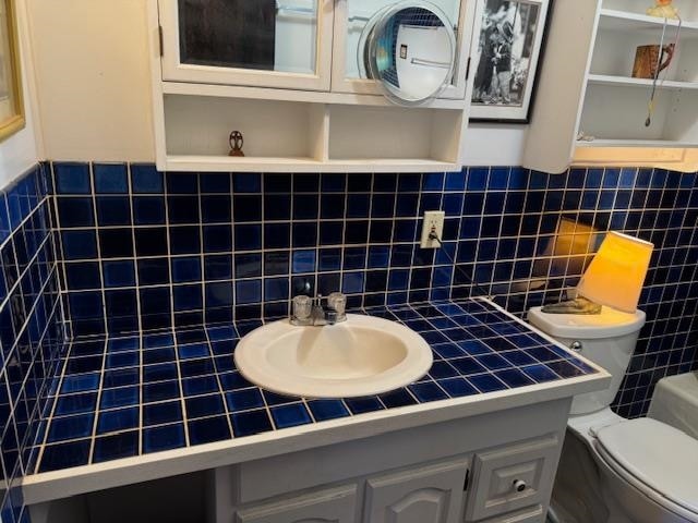 bathroom with decorative backsplash, vanity, tile walls, and toilet