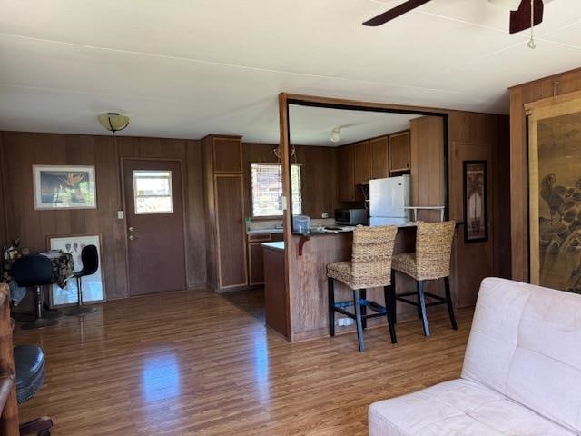 kitchen with white refrigerator, dark hardwood / wood-style floors, ceiling fan, a kitchen bar, and kitchen peninsula