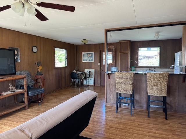 kitchen with hardwood / wood-style flooring, wooden walls, a breakfast bar area, and a wealth of natural light