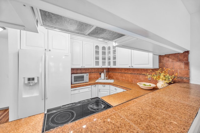 kitchen featuring white appliances, glass insert cabinets, white cabinetry, a sink, and backsplash