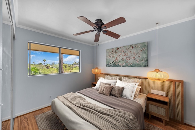 bedroom featuring crown molding, a ceiling fan, baseboards, and wood finished floors