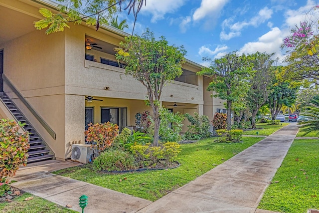 view of home's exterior featuring ac unit, stucco siding, a yard, and stairway