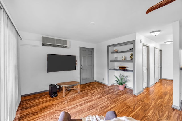 living room featuring baseboards, a wall mounted AC, and light wood-type flooring