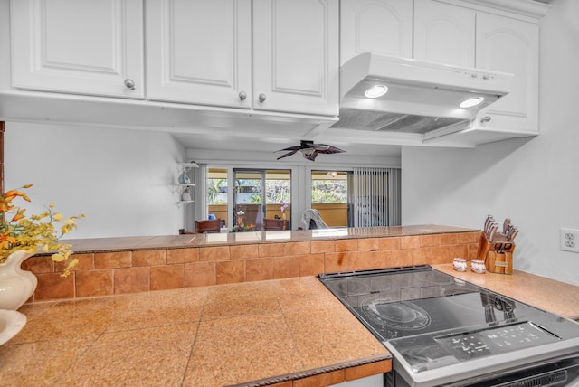 kitchen with under cabinet range hood, white cabinets, and range with electric stovetop