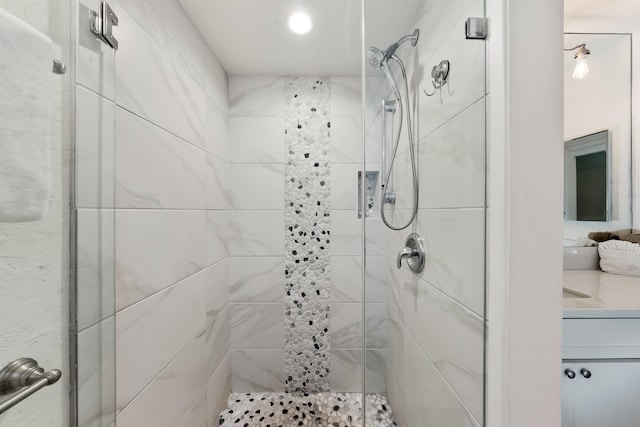 bathroom featuring a shower with shower door and vanity