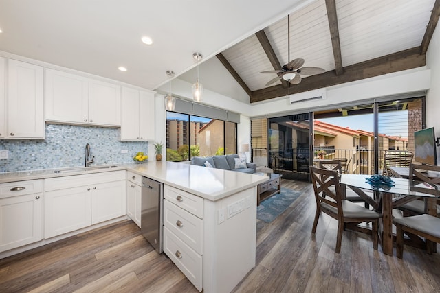 kitchen with dark hardwood / wood-style flooring, kitchen peninsula, sink, lofted ceiling with beams, and pendant lighting