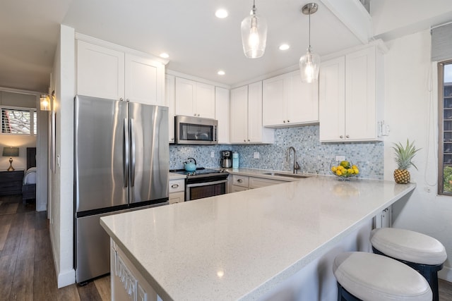 kitchen with dark wood-type flooring, appliances with stainless steel finishes, decorative light fixtures, sink, and tasteful backsplash