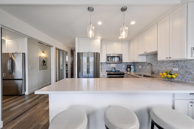 kitchen with dark hardwood / wood-style flooring, appliances with stainless steel finishes, pendant lighting, sink, and tasteful backsplash