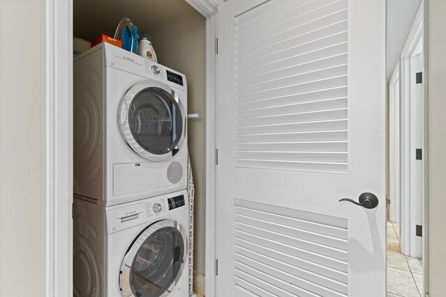 clothes washing area featuring light tile patterned floors and stacked washing maching and dryer