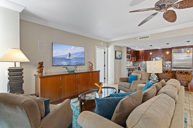 living area featuring baseboards, ceiling fan, visible vents, and ornamental molding
