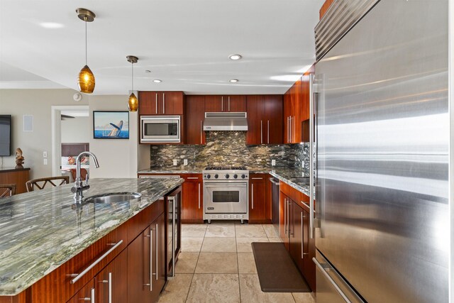 kitchen with built in appliances, sink, hanging light fixtures, a center island with sink, and light tile patterned flooring