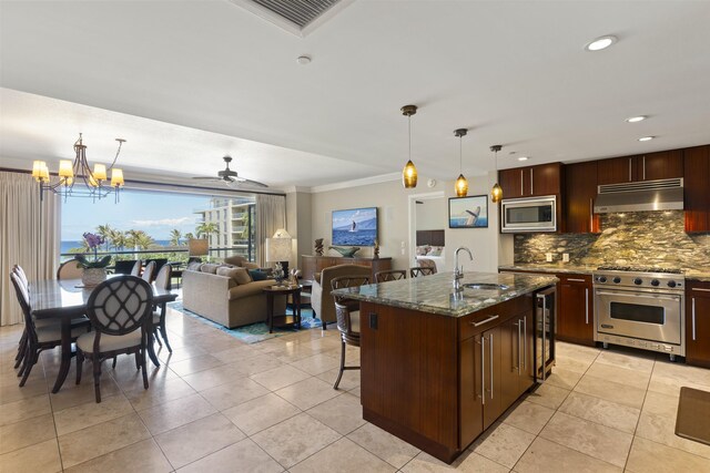 kitchen with a kitchen island with sink, dark stone counters, tasteful backsplash, sink, and appliances with stainless steel finishes