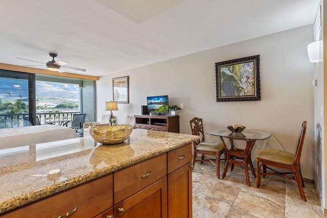 kitchen with ceiling fan and light stone counters