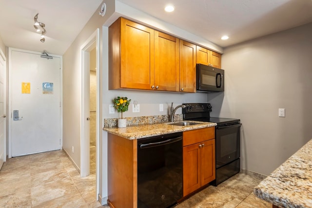 kitchen with light stone counters, sink, and black appliances