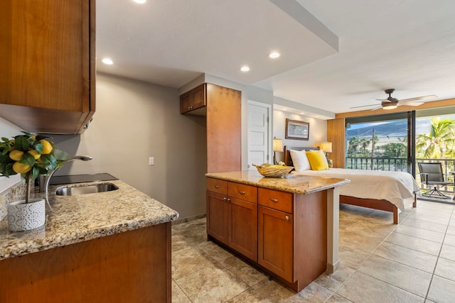 kitchen with light stone counters, sink, and ceiling fan